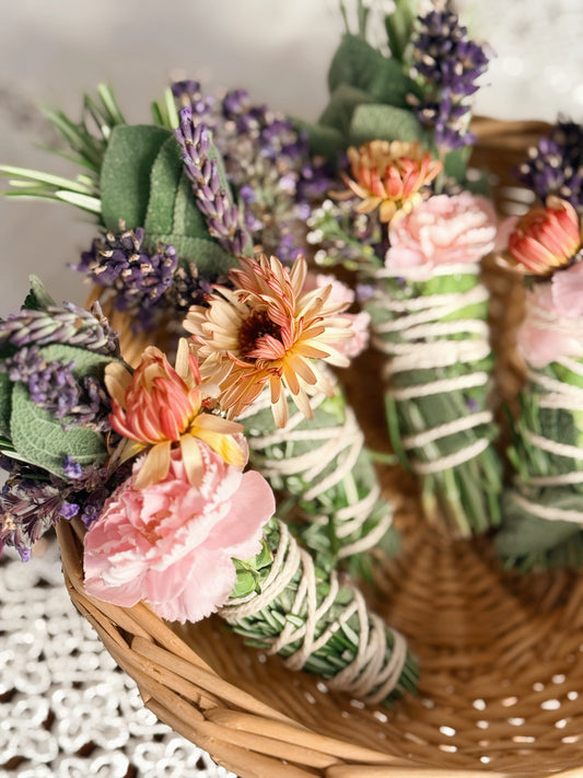 Decorative bundle of flowers and greenery in a woven basket on a textured surface.