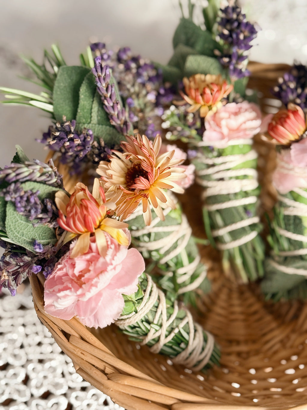 Decorative bundle of flowers and greenery in a woven basket on a textured surface.