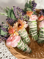 Decorative bundle of flowers and greenery in a woven basket on a textured surface.