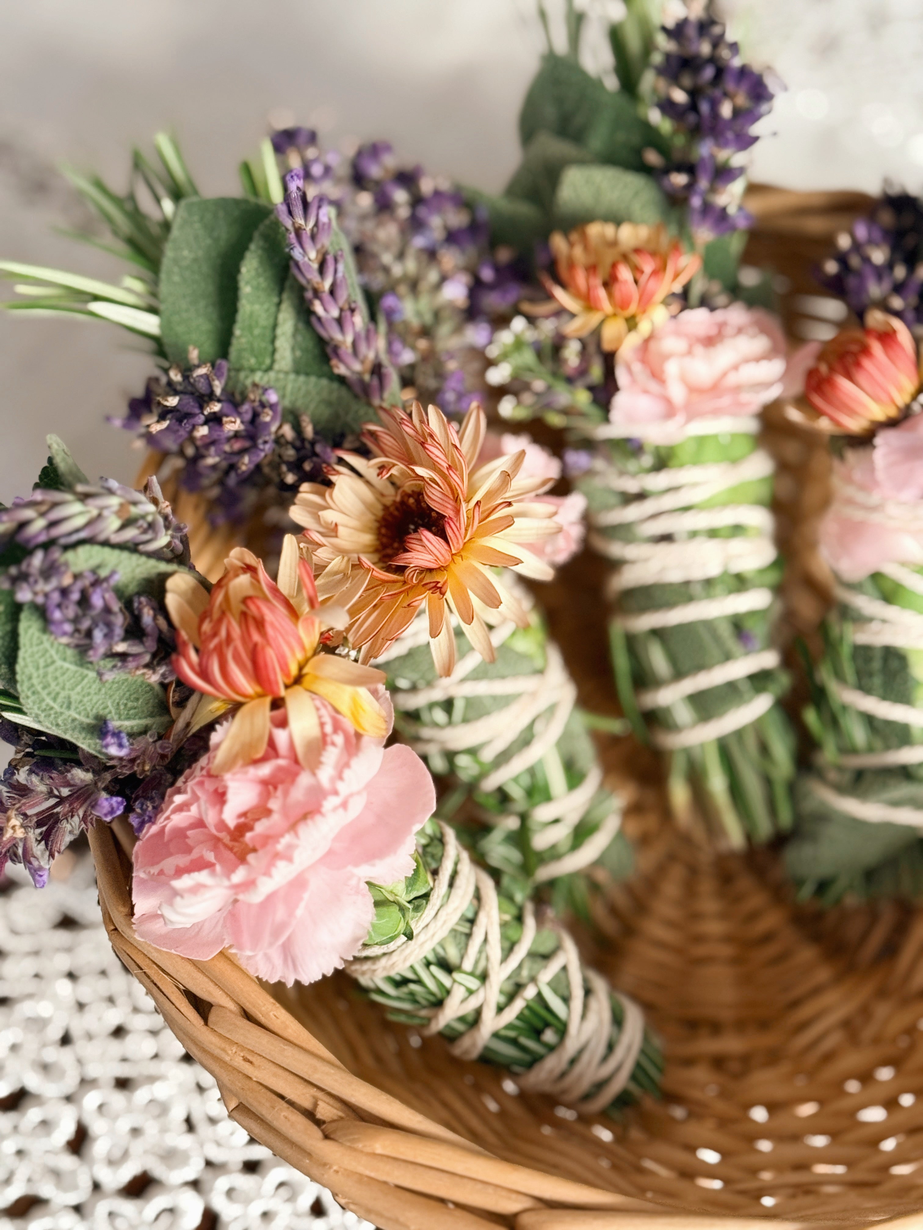 Decorative bundle of flowers and greenery in a woven basket on a textured surface.