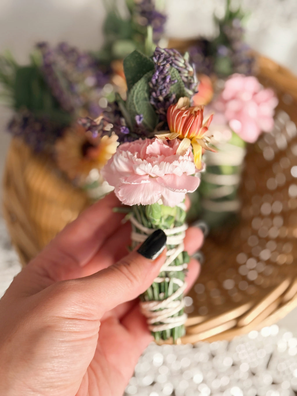 Hand holding a small bouquet of flowers with a blurred floral background